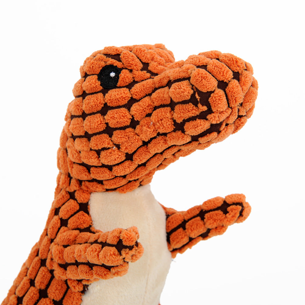 Close-up of the orange Jurassic Chew dinosaur dog toy's face, highlighting its soft corn velvet material and durable construction. White background.